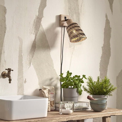 Applique murale Java en bambou tressé noir et naturel installée au-dessus d'un plan de travail, lumière chaude diffusée à travers le tressage