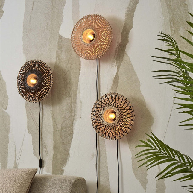 Trois appliques murales en bambou tressé, effet spirale lumineux, disposées sur un mur d'esprit bohème avec plantes vertes