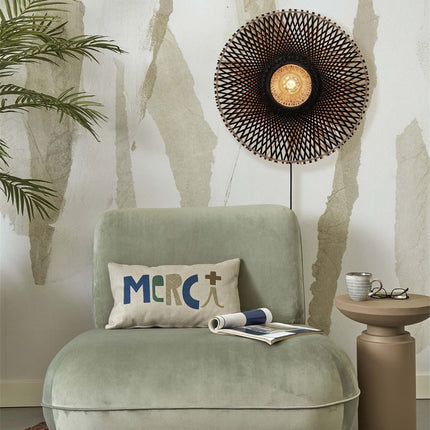 Lit Kalimantan black and natural woven bamboo wall light above a green armchair in a living room
