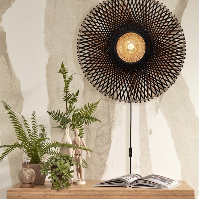 Lit Kalimantan wall light with black fabric cable and inline switch above a wooden cabinet