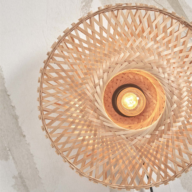 Vue de face de l'applique Kalimantan, tressage en spirale de bambou naturel autour de l'ampoule allumée