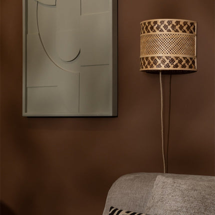 Applique murale en bambou tressé naturel et brun fixée sur un mur de couleur terracotta