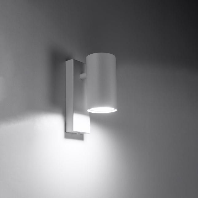 White wall light switched on casting a halo of soft light downward onto the wall