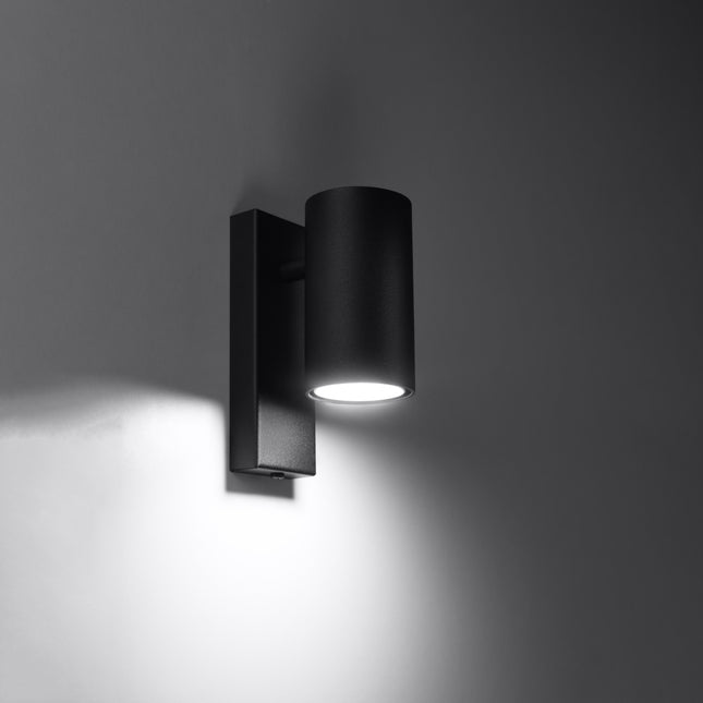 Lit black wall light casting a halo of soft light downwards on the wall
