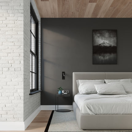 Applique liseuse acier noir dans une chambre loft aux murs sombres et briques blanches