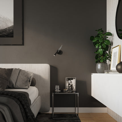 Applique liseuse acier noir installee au chevet d'un lit dans une chambre japandi