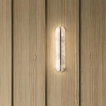 Applique murale en marbre allumée sur un mur en bois clair, lumière chaude et tamisée