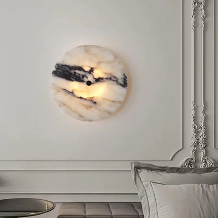 Applique murale en marbre naturel allumée au dessus d'une tête de lit sur un mur mouluré classique