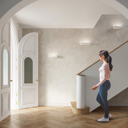 Appliques murales céramique blanche rythmant une montée d'escalier lumineuse