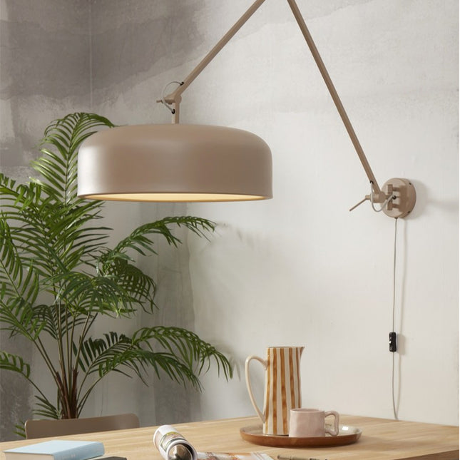 Sand iron Marseille wall light above a wooden dining table, warm atmosphere