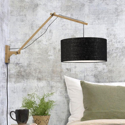 Applique murale Andes au bras en bambou articulé au-dessus d'un lit, abat-jour noir diffusant une lumière tamisée