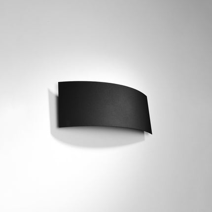 Applique murale Arc noire vue de face, lame d'acier courbée contre un mur gris clair