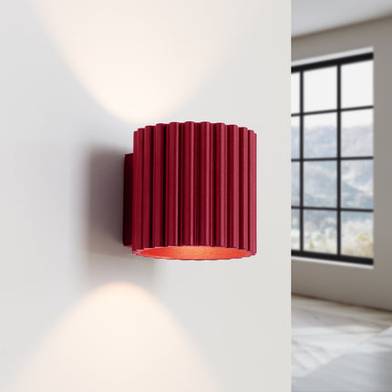 Applique AURA bordeaux diffusant sa lumière vers le haut et le bas sur un mur clair