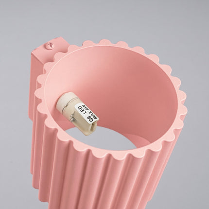 Applique murale Aura cannelée aluminium rose poudré, vue sur fond coloré