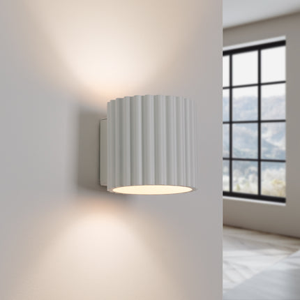 Applique murale Aura allumée diffusant une lumière chaude vers le haut et le bas du mur