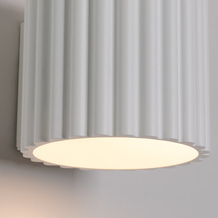 Gros plan sur les cannelures blanches et le diffuseur lumineux de l'applique Aura
