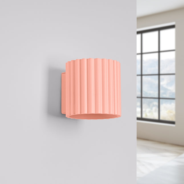 Applique murale Aura pêche posée sur un mur clair près d'une fenêtre, lampe éteinte