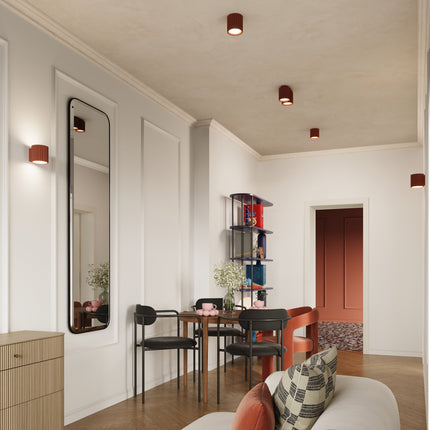 Applique Aura rouge ocre allumée sur un mur blanc d'un intérieur clair avec miroir