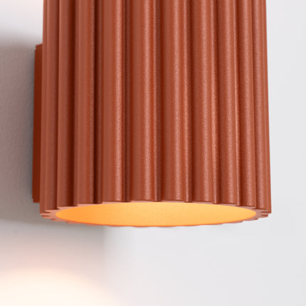 Détail des cannelures et de l'ouverture basse de l'applique Aura rouge ocre sur mur clair