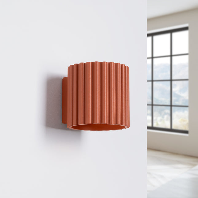 Applique murale Aura rouge ocre installée sur un mur blanc près d'une fenêtre