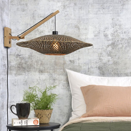 Applique murale Bali en bambou tressé naturel et noir installée au-dessus d'une table de chevet dans une chambre