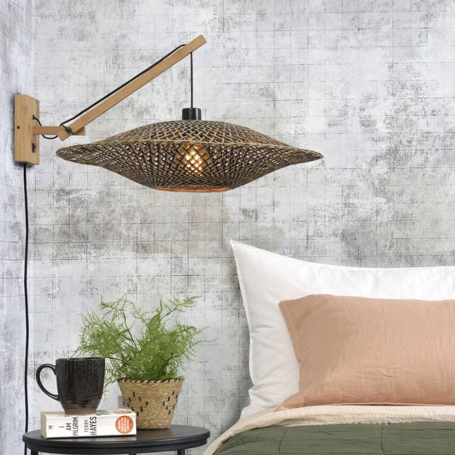 Applique murale Bali en bambou tressé naturel et noir installée au-dessus d'une table de chevet dans une chambre