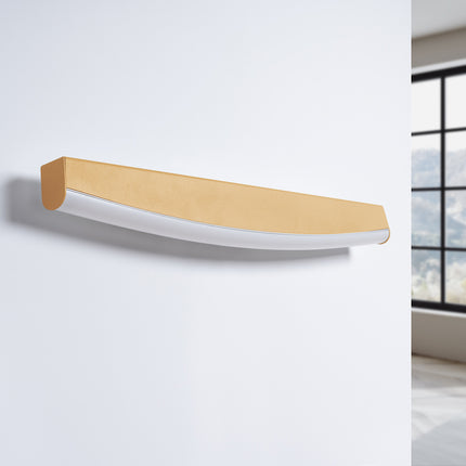 Applique murale barre courbée dorée vue de trois quarts, éteinte sur un mur blanc