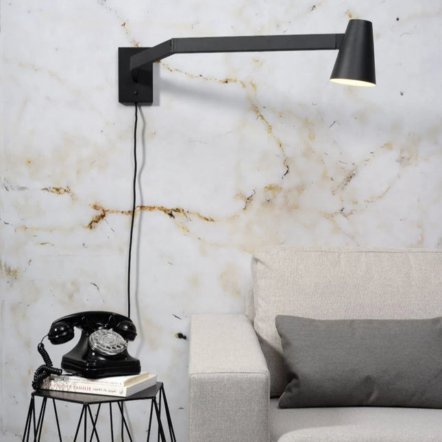 Applique murale Biarritz en fer noir installée au dessus d'un canape gris