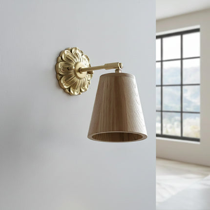 Applique murale Sovala en bois de frêne et laiton, abat-jour conique orientable posé contre un mur clair