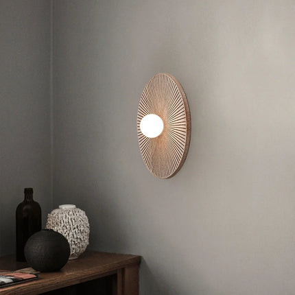 Applique murale ronde en bois massif éclairée dans une entrée décorée de vases en céramique et grès