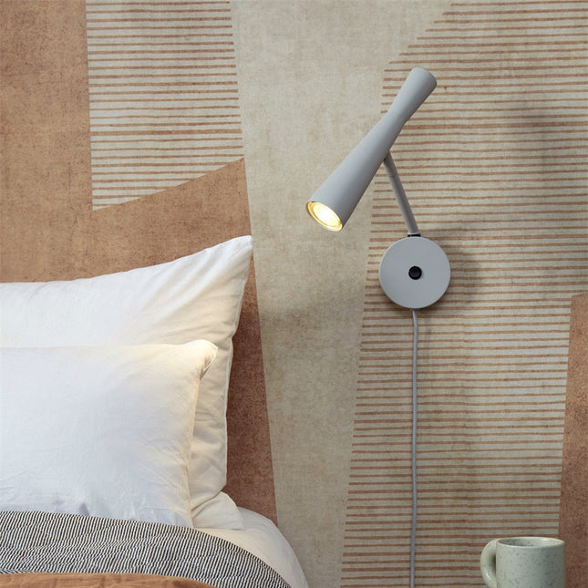 Applique murale Bordeaux gris clair fixee en tete de lit, lumiere chaude orientee vers le livre