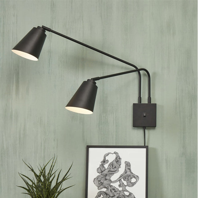 Applique murale Bremen à deux bras en fer noir sur un mur vert dans un salon