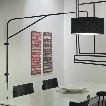 Applique murale Brighton au bras articulé en fer noir et abat-jour en coton, déployée au-dessus d'une table à manger