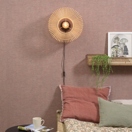 Applique murale Bromo en bambou tressé installée au-dessus d'une tête de lit dans une chambre
