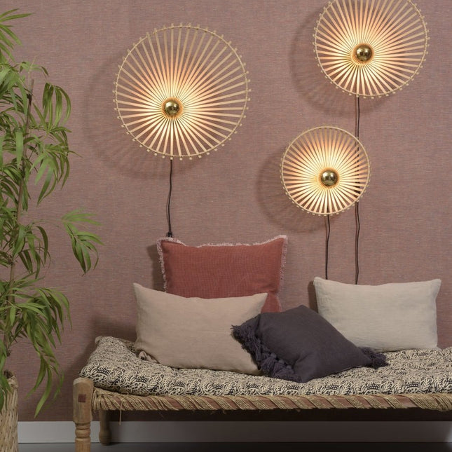 Three braided bamboo wall lights of various sizes, arranged on a pink wall above a bench seat