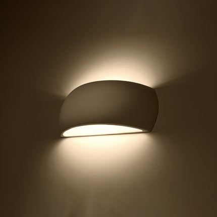 Applique Carapace en céramique allumée diffusant une lumière chaude vers le haut et le bas sur un mur