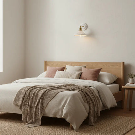 Applique murale en céramique blanche allumée au-dessus d une tête de lit en bois clair, ambiance chambre douce