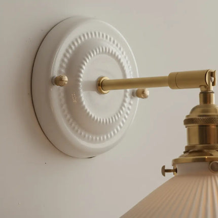 Gros plan sur la platine céramique perlée et le bras articulé en laiton doré de l applique murale