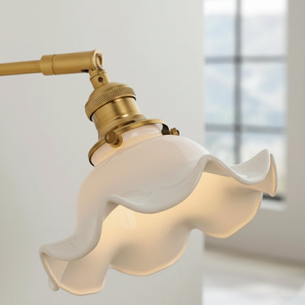 Détail de l abat-jour en céramique blanche ondulée et de la douille en laiton doré allumés