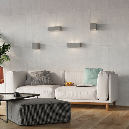 Composition d'appliques murales grises au-dessus d'un canapé clair dans un salon contemporain