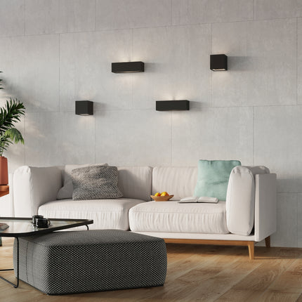 Quatre appliques murales céramique noire disposées au-dessus d'un canapé dans un salon