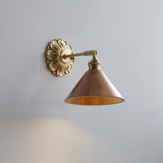 Applique murale conique en bois clair avec rosace en laiton doré, abat-jour orientable sur mur gris