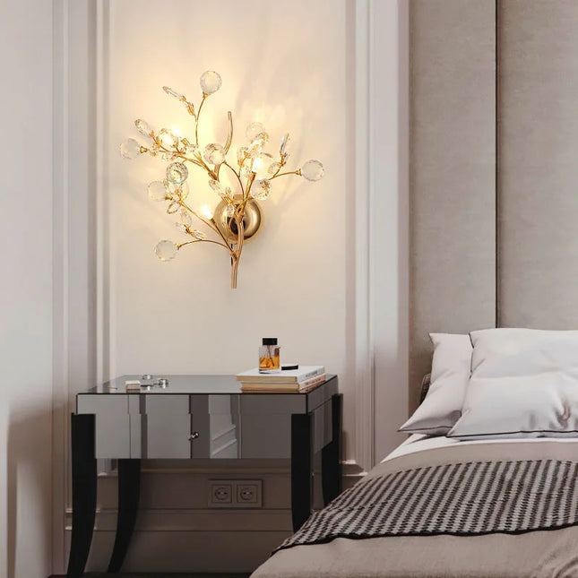 Applique en cristal doré diffusant une lumière chaude au-dessus d'une table de chevet dans une chambre