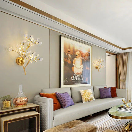 Paire d'appliques murales branches en cristal doré de part et d'autre d'un cadre au-dessus d'un canapé