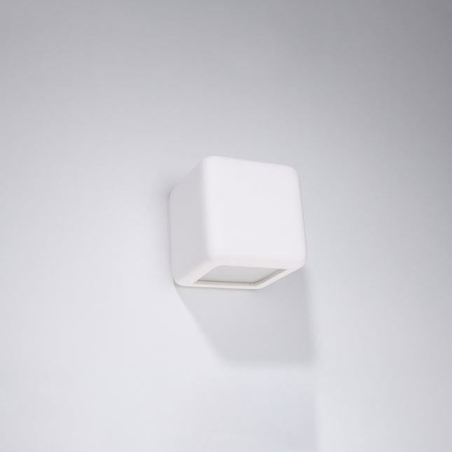 Applique cube céramique blanche fixée sur un mur clair, éclairage bidirectionnel eteint