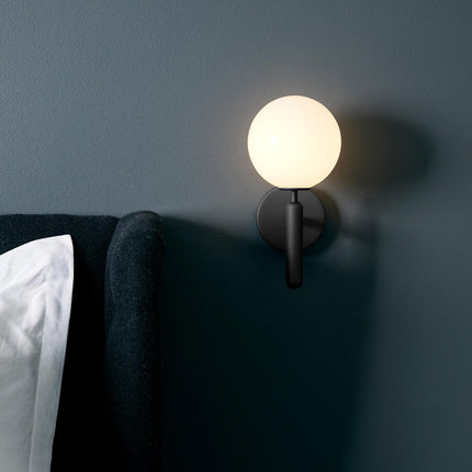 Applique murale cylindre moderne noire fixée près d'un lit