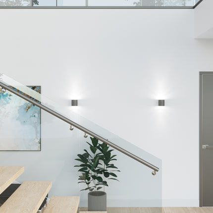 Détail rapproché d'une applique cylindrique anthracite allumée au mur