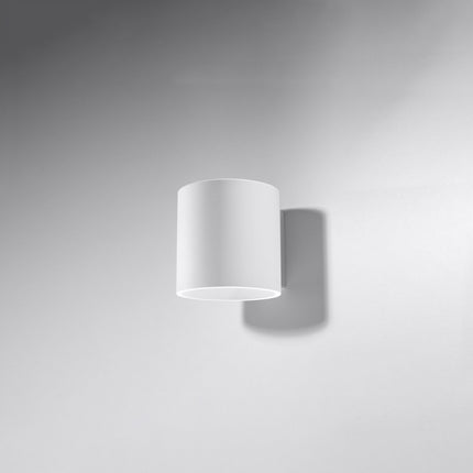 Applique murale cylindrique blanche allumée dans un salon lumineux