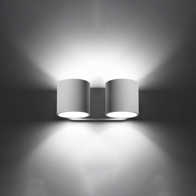 Applique cylindrique double blanche allumée de face, faisceaux lumineux projetés vers le haut et vers le bas.