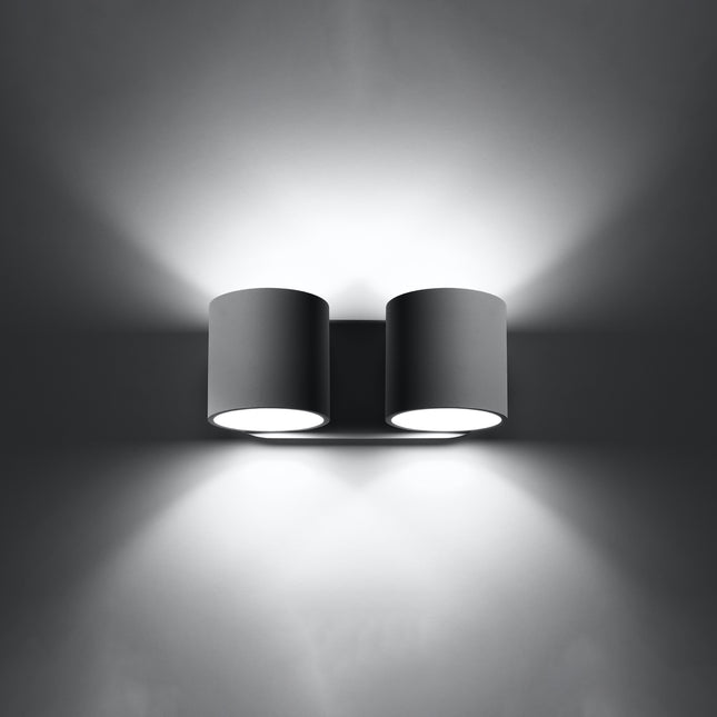 Applique cylindrique double grise allumée de face, faisceaux lumineux projetés vers le haut et vers le bas.